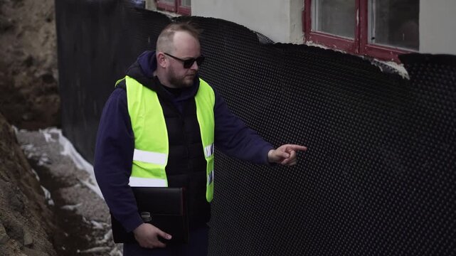 Construction inspector identifies defects on an exterior wall during a site inspection, useful for building quality control and renovation planning.