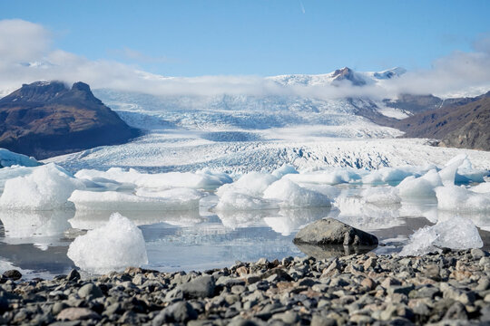 Volcanic rock shore with melting icebergs and glacier Face at glacial lagoon, J&ouml;kuls&aacute;rl&oacute;n, Iceland