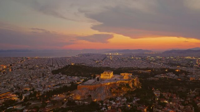 Stunning aerial perspective of the ancient acropolis and the iconic parthenon, illuminated against the sprawling cityscape of athens as the sun sets with vibrant orange and purple colors