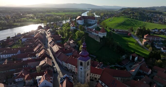 Ptuj Castle in historic Old Town surrounded by red rooftops, vineyards and the Drava River in Ptuj city, Slovenia. Aerial pull out shot