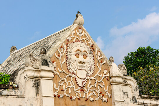 
Ancient temple face carves intricate designs above a tiled roof at Tamansari Water Castle Yogyakarta. Birds perch atop stone walls, adding quiet life to the scene. Ceremonial carvings show joy, rever