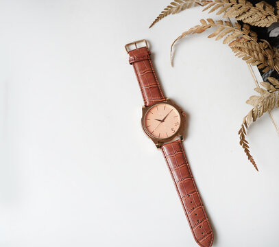 Top view of elegant rose gold men watch with brown leather strap on white table with copy space