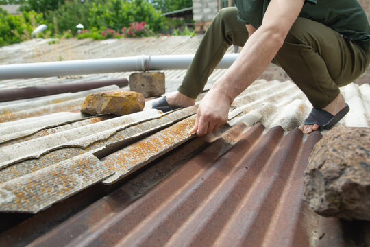 Man repair old asbestos slate roof.