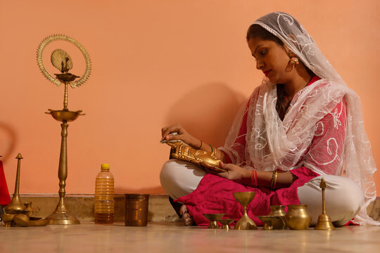Woman cleaning brass items in preparation for a traditional ceremony.