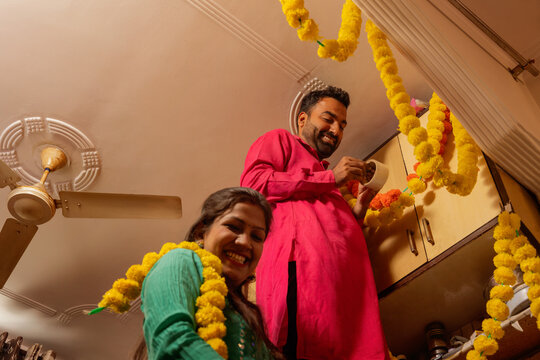 Couple smiling while decorating kitchen for festival.