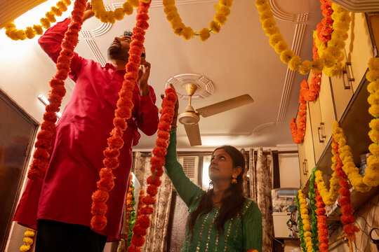 Couple arranging garlands in kitchen for celebration.