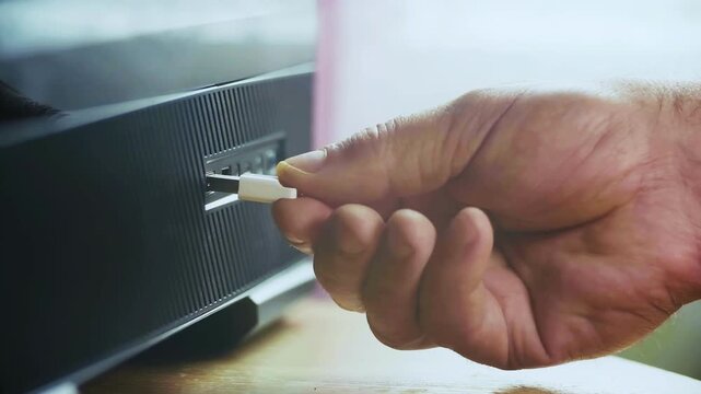 The image shows a hand holding a USB stick inserted into the device.