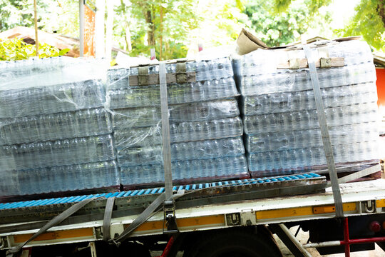 Plastic bottle water pallet packaging transportation delivery truck outdoor supply Wrapped plastic water bottles stacked pallet secured with straps delivery truck outdoor setting showing supply