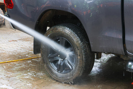 Car wheel cleaning water spray black tire outdoor vehicle wet Car wheel cleaning with water spray black tire and rim outdoor vehicle wash wet pavement maintenance fresh and shiny appearance