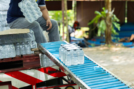 Plastic bottle water conveyor packaging factory production transport worker outdoor efficiency hydration supply beverage blue transparent liquid distribution pallet machinery