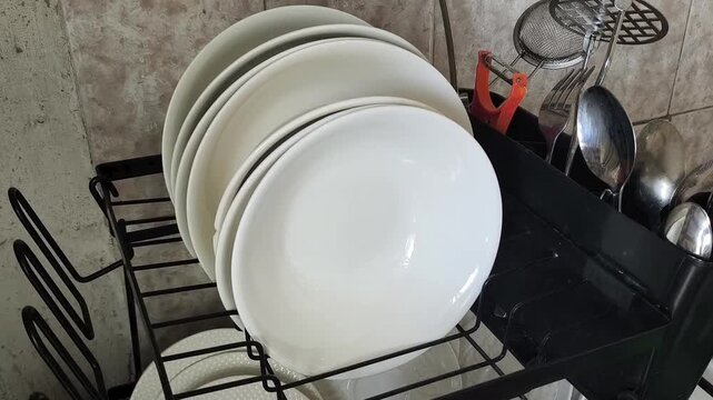 Clean plates and spoons drying on a kitchen dish rack, organized home kitchen, household routine and daily life concept.