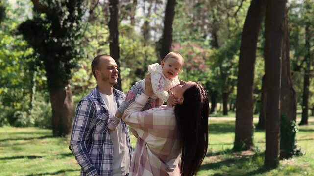 Happy family with baby daughter enjoying time together in sunny park