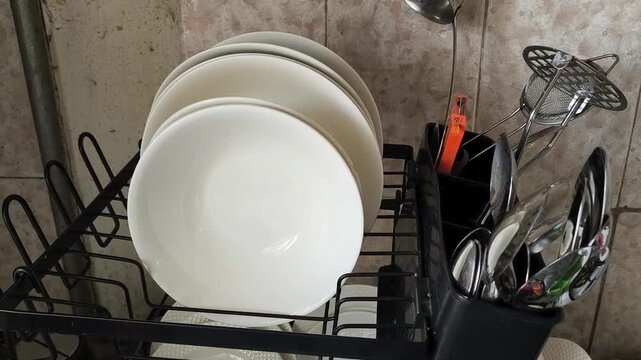 Clean plates and spoons drying on a kitchen dish rack, organized home kitchen, household routine and daily life concept.