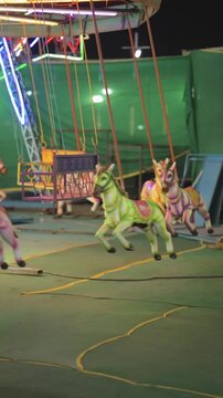 Carousel horse ride at night fair, Colorful merry go round horse closeup, Kids amusement ride in carnival lights, Mela jhula horse carousel at night stock video.