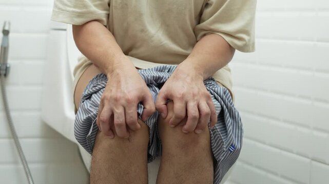 portrait of a man suffers from diarrhea his stomach painful. ache and problem. of toilet bowl. constipation in bathroom. Hygiene, health care concept.