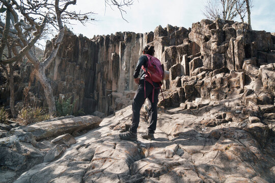 Hiker stands before impressive basalt rock wall
