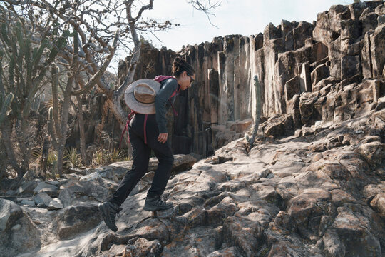 Woman hiking up a steep rocky desert hill with columnar basalt