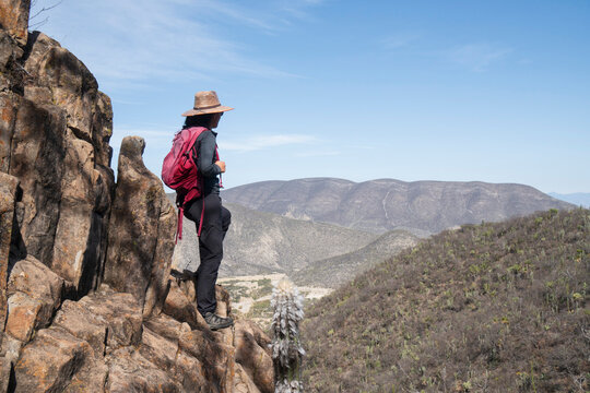Female hiker on a cliff overlooking mountains