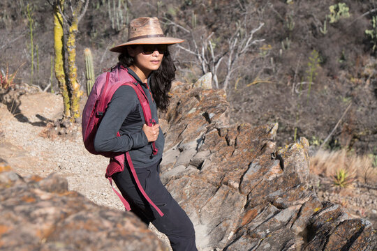Woman in a sun hat hikes a rocky desert trail