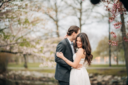 Engaged couple embracing in a spring cherry blossom park