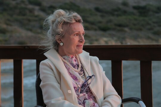 Elegant senior woman enjoys the sunset from a balcony