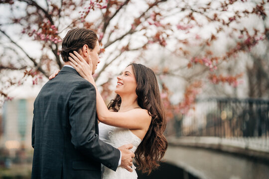 Newlywed couple embracing under pink blossom tree