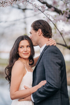 Loving couple embracing outdoors under cherry blossoms
