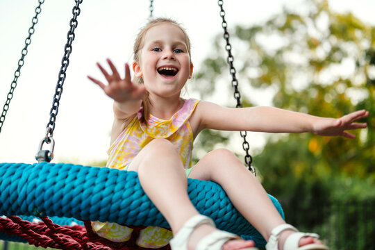 Happy little girl playing on rope swing at playground