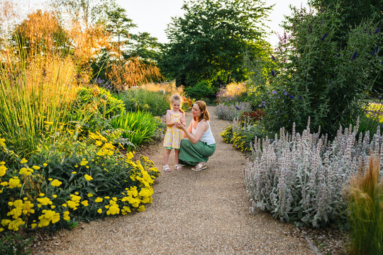 Mother and daughter exploring blooming summer garden