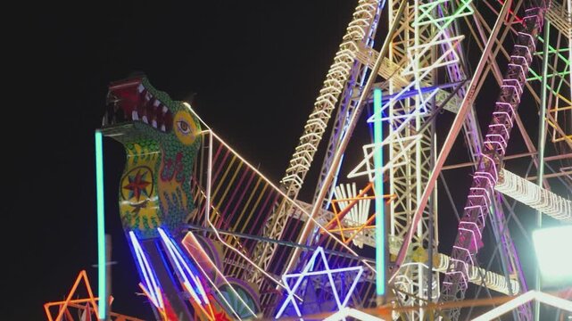 Giant swing ride at night fair, Colorful mela jhula under night sky, Illuminated amusement ride at carnival, Fairground thrill ride with neon lights stock video. 