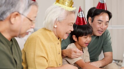 Fototapeta premium Multigenerational Asian Family Wearing Party Hats Celebrating a Birthday Together