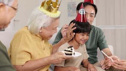 Fototapeta premium Multigenerational Asian Family Celebrating a Birthday with Cake and Party Hats