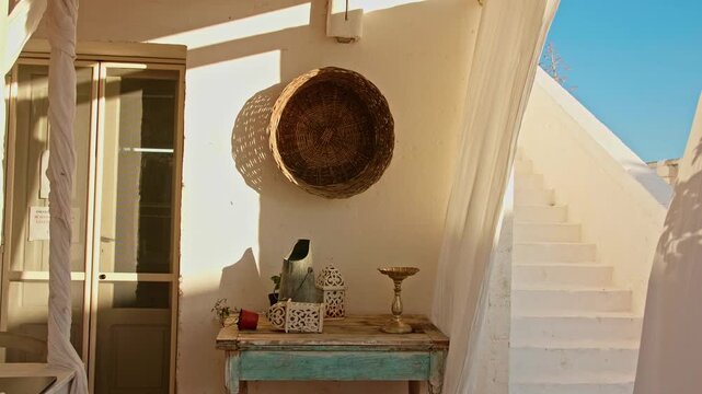 Charming corner in a typical whitewashed village in puglia, italy. Sunlight casting shadows over rustic furniture and white stairs