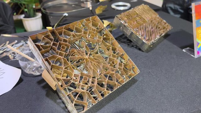 A craftsman creates a copper batik stamp. This traditional Malay art tool is dipped in hot wax to stamp patterns onto fabric. It saves time compared to hand-drawing.