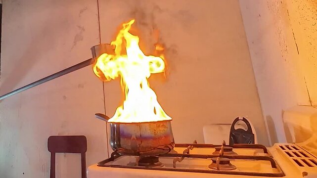 Kitchen fire safety hazard with a pot of burning oil on a stove. A large explosion occurs when water is added to the pot. Very dangerous situation.