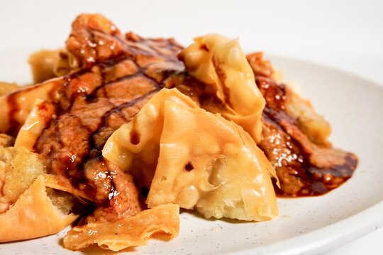 Close up batagor crispy Indonesian snack with peanut sauce isolated on horizontal white background.