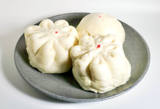 Three baozi dimsum breads on gray plate isolated on horizontal white background.