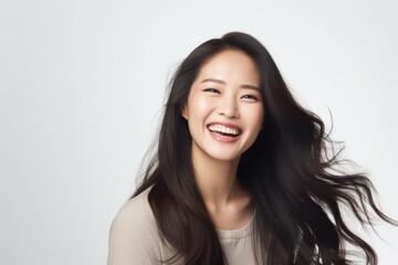 Fototapeta premium Young asian woman posing with a genuine laugh and long flowing hair on a white background