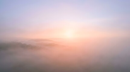 Fototapeta premium Early morning mist blankets a serene landscape, illuminated by a gentle gradient of dawn light