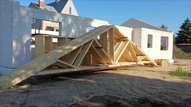 Construction of house with aerated concrete block walls and wooden roof trusses on site, residential property development concept.