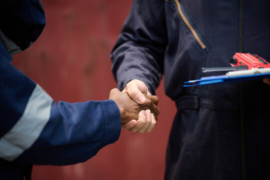 Closeup engineers or workers shaking hands in containers warehouse storage
