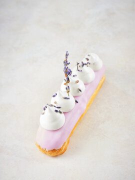 Lavender eclair with whipped cream and lavender garnish for upscale dessert menu, patisserie concept