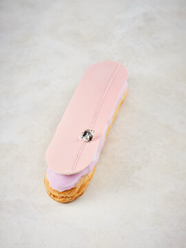 Pink eclair with cream filling and decorative topping, dessert menu, special occasion treat
