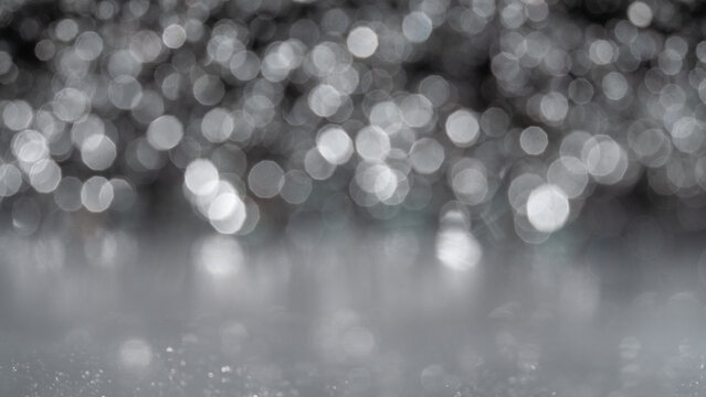 Bright lights reflect on a wet surface creating a bokeh effect during the evening hours