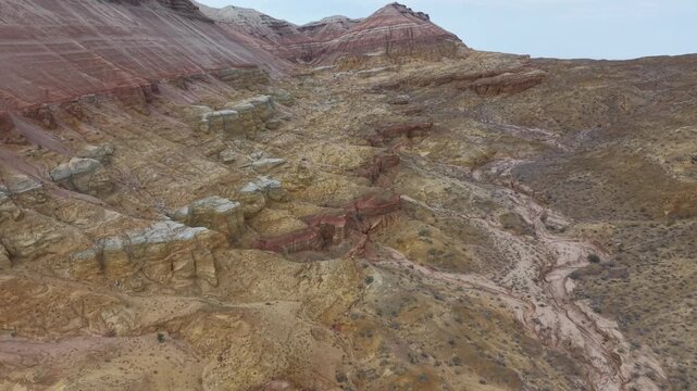Aerial drone footage of the colorful Aktau Mountains in Altyn Emel National Park, Kazakhstan. Dramatic desert landscape with striped clay hills, rocky formations and scenic travel destination atmosphe