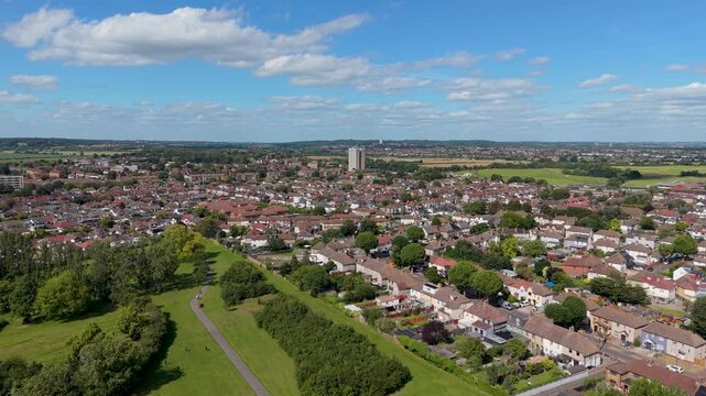 Drone flyover of Chad Park, Chadwell Heath, moving forward toward Highview House tower block near the A12, showing suburban rooftops, green space, and clouds over east London, UK.