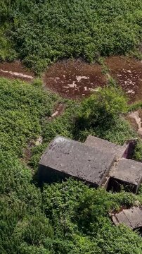 WWII anti-aircraft battery ZE1 gun emplacements at Chadwell Heath, London&mdash;close forward vertical drone flyover of ruins, concrete hardstands and overgrown scrub at historic Blitz-era defense site.