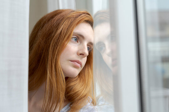 Portrait of serious young woman looking out of window