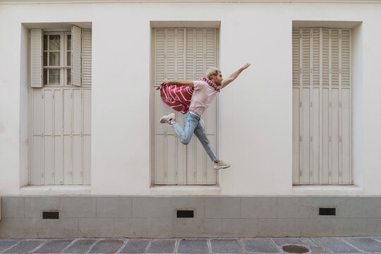 Young man jumping over footpath as superhero