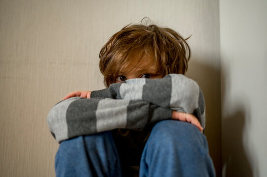Sad boy sitting in corner at home